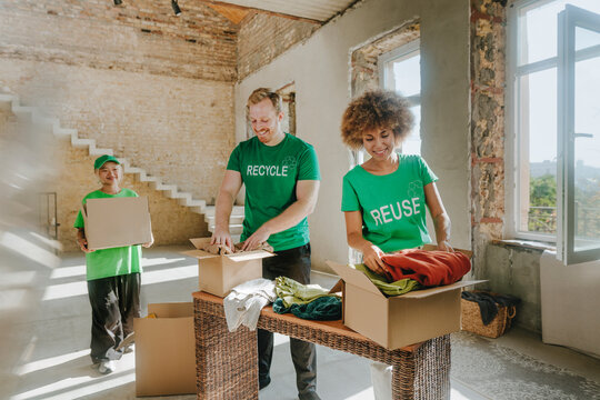 Smiling activists stacking clothes in donation boxes at apartment