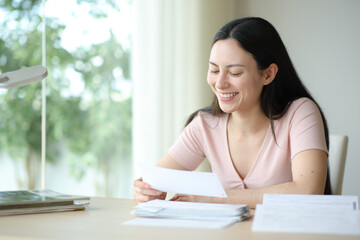 Happy asian woman cheking bill at home