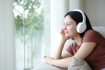 Asian woman relaxing listening audio looking through a window