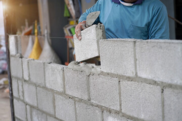 masonry worker make concrete wall by cement block and plaster at construction site