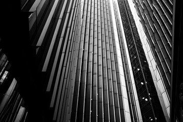 A dramatic black-and-white photo showcasing the vertical lines and reflective surfaces of modern skyscrapers, highlighting architectural symmetry and urban design allure 
