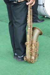 A male musician holding a saxophone in the back