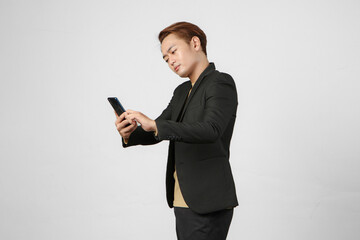 portrait of pensive thoughtful asian businessman wearing suit holding mobile phone on isolated background.