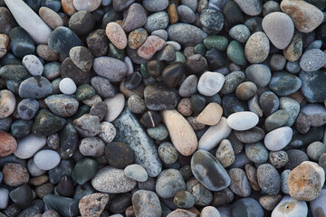 A close-up of a collection of smooth, multicolored pebbles and stones. These natural beach rocks display a variety of earthy tones and textures, creating a calming and organic aesthetic.