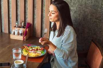 Young woman enjoying delicious breakfast in a restaurant