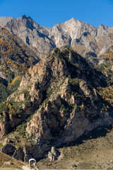 Chegem Gorge. Kabardino-Balkaria. El-Tyubu. Unique rocky ridge with steep cliffs against blue autumn sky.Rocky mountains with trees growing on their slopes glow in morning sun.