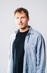 Confident young man on neutral backdrop. A young man with tousled hair stands confidently in casual...