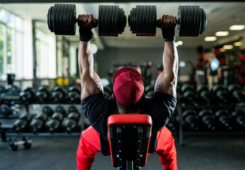 Afternoon gym weightlifting session. A person is lifting heavy weights in a gym filled with...