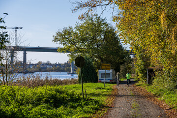 Wanderweg am Ufer des Nord-Ostsee-Kanals im Herbst, zwei Radfahrer fahren an einem Campinwagen vorbei