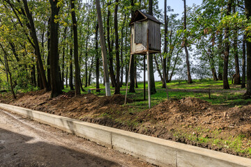 A wooden box is on a post in a wooded area