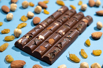 Nutty milk chocolate among scattered almonds, raisins and hazelnuts.