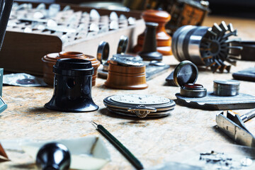 Tools surround pocket watch on wooden workbench