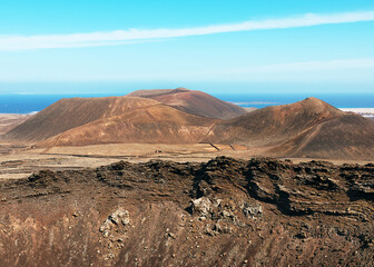 View on dramatic volcanic red deserted crater of Calderon Hondo volcano and distant mountains near to Corralejo. La Olivia, Fuerteventura. Spain