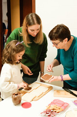 Three women are making sandwiches with chocolate spread