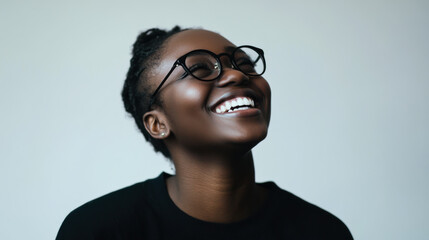 Fototapeta premium A young woman with glasses smiles warmly, showcasing joy and confidence against a soft light background in a candid indoor setting