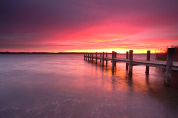 Obraz premium long wooden rustic pier at the lake with amazing purple sky