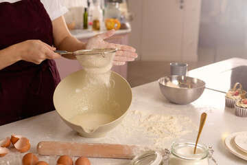 Baker sifts flour into a bowl for cake making