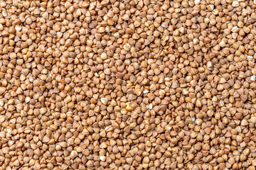 Buckwheat Grains on Plate on Wooden Background, Top View, Copy Space.Hulled kernels of buckwheat grains close up. Food background.