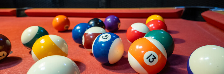 Vibrant billiard balls scattered on a red pool table symbolize the excitement of game night and the challenge of strategic play