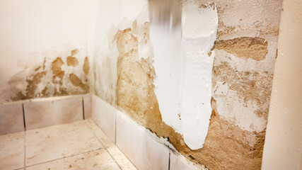 A close-up of a wall being repaired with plaster to fix water damage, highlighting home renovation and maintenance issues