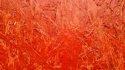Close-up of a textured red plywood surface, symbolizing vibrancy and creativity, ideal for interior design or artistic projects