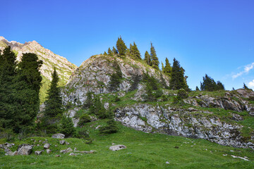 Idyllic summer landscape with hiking trail in the mountains with beautiful fresh green mountain pastures and rocks.