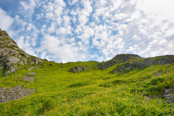 Idyllic summer landscape with hiking trail in the mountains with beautiful fresh green mountain pastures and clouds.