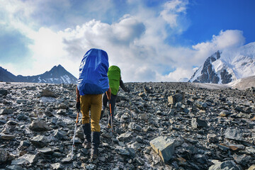 People go up to mountain on the glacier under clouds. High mountain view.