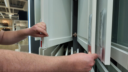 A person examines kitchen cabinet doors in a showroom, highlighting home renovation and interior design inspiration