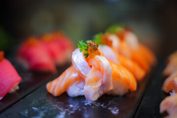 Salmon nigiri sushi in plastic box packaging tray on black stone slate background