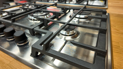 Close-up of a stainless steel gas stove with four burners, illustrating efficient kitchen design and energy conservation