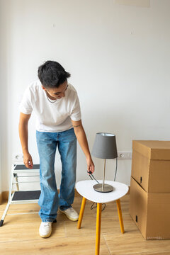 Trans man setting up lamp in new apartment