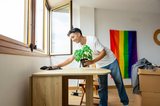 Trans man settling into a new home with pride flag in background