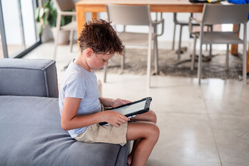 Young boy engrossed in using a tablet indoors