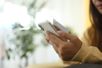 Cropped shot young woman shopping online with smartphone and credit card