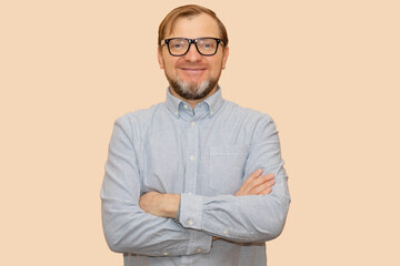 Portrait of smiling middle age 40 - 45 years old man. Mid adult, happy mature age male with gray beard and glasses. Isolated on pastel beige background, copy space.
