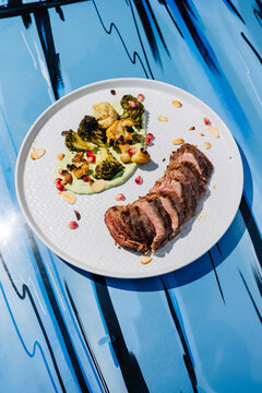 Sliced of Filet mignon beef steak with roasted vegetables on blue background