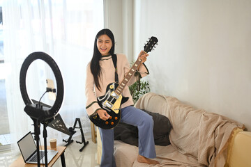 Young cheerful woman playing electric guitar during a live session