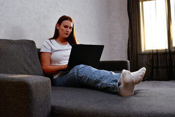 A young woman works from home on her laptop, focused on her tasks. This moment reflects the convenience and freedom of remote work in a comfortable setting.