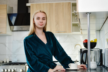  A young woman enjoys fresh aromatic coffee in her cozy kitchen. The concept of a morning ritual that awakens the senses and creates an atmosphere of comfort and inspiration for the day ahead.