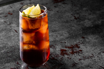 A refreshing glass of iced tea with lemon slices on a dark, textured surface. The drink is garnished with fresh mint leaves, creating a perfect summer beverage. Ideal for food and drink categories.
