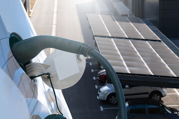 Naklejka premium Electric car is charging from a charging station that takes energy from solar panels. Close up.