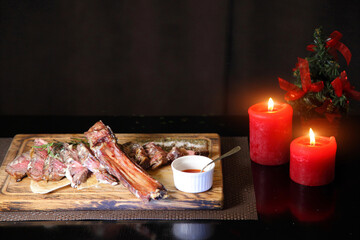 Christmas steak by candlelight. Christmas atmosphere and the mood to eat delicious steaks. Beef steak on a wooden board. Christmas table and steak.