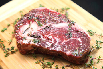 Raw aged steak. A raw, aged steak on a wooden board awaits to be cooked.