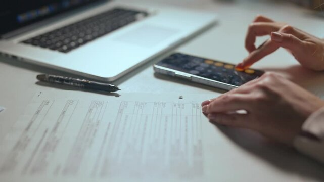 Accountant, businesswoman or banker using calculator, checking paperwork and documents while preparing financial data report in an office. Hands of a woman doing payroll or calculating annual tax