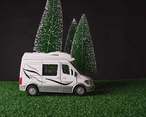 Model of camper at night on black background with snowy fir trees. Christmas night, winter...