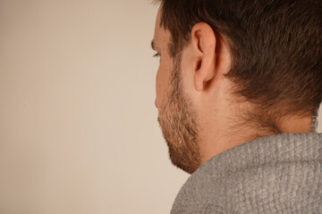 Obraz premium Neutral background. Male in casual clothes. Young guy standing in front of camera. Man looking at side. Head from back side. Side view. Handsome man.