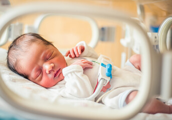 Peaceful newborn baby in hospital incubator with medical equipment. Prematurity awareness month. World prematurity day 17 november