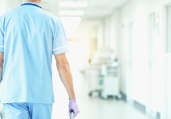 Fototapeta premium Healthcare worker in scrubs and gloves walking down a hospital corridor