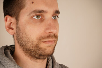 Obraz premium Face with a birthmark. Handsome guy. Side view. Neutral background. Man in casual clothes. Young man standing in front of camera. Human looking at side.